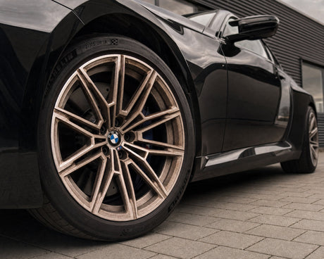 Rostbrauner Bremsstaub-Film auf der silbernen Alufelge eines schwarzen BMW M2 — gezeigt im Artikel „Alufelgen reinigen: welche Oberfläche du wirklich hast“