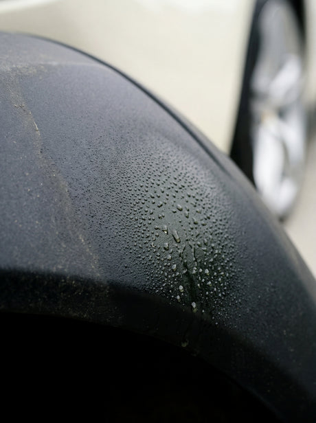 Green Star Reinigungslösung auf schwarzem Kunststoff-Radlauf am Ferrari